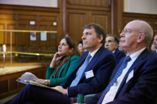 Rt. Hon. John Glen MP, Minister for the Cabinet Office, and Nick Smallwood, CEO of the IPA, sit in an auditorium as part of the audience at the TIP Live event. 